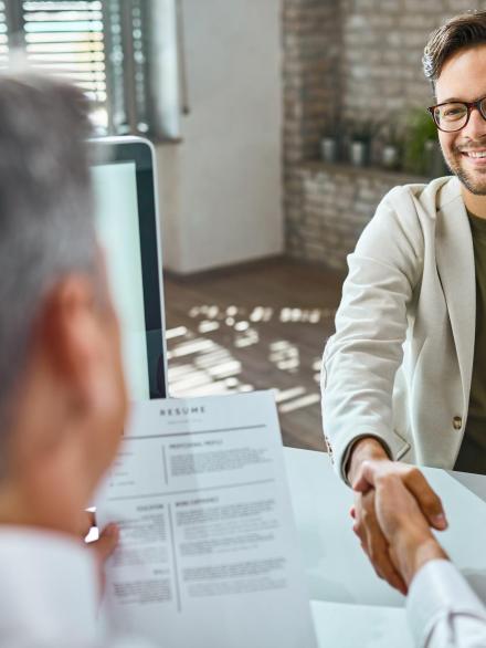 Happy male candidate greeting a member of human resource team on a job interview in the office.